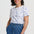 Woman wearing a white t-shirt with blue patterns and blue pants on a white background
