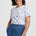 Woman wearing a white t-shirt with blue patterns and blue pants on a white background