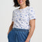 Woman wearing a white t-shirt with blue patterns and blue pants on a white background