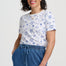 Woman wearing a white t-shirt with blue patterns and blue pants on a white background
