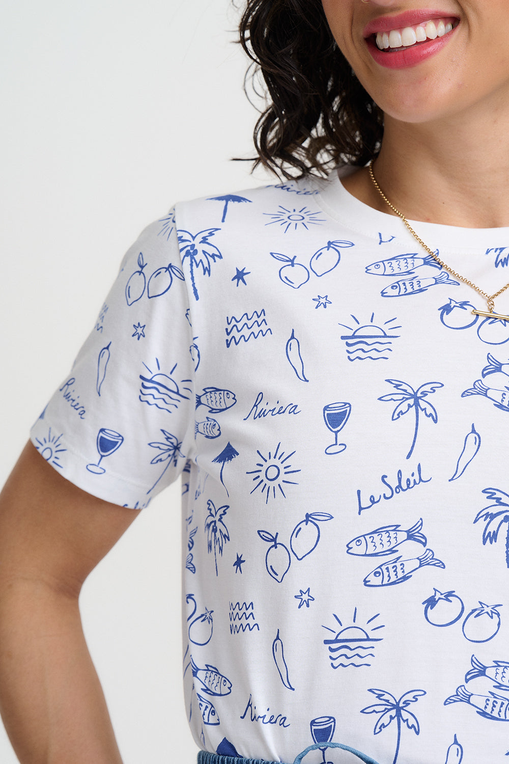 Person wearing a white t-shirt with blue illustrations on a plain background