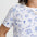 Person wearing a white t-shirt with blue illustrations on a plain background