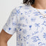 Person wearing a white t-shirt with blue illustrations on a plain background