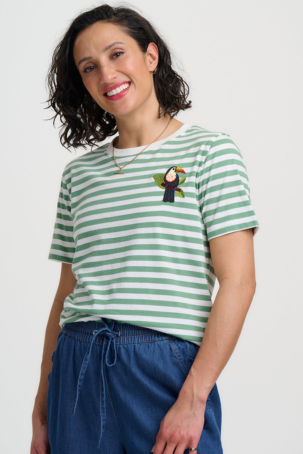 Woman wearing a green and white striped t-shirt with a penguin design on a plain background