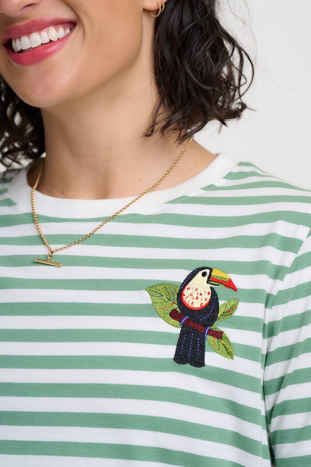 Person wearing a green and white striped shirt with a toucan design, smiling.