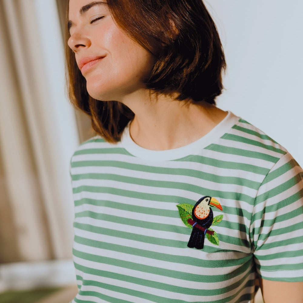 Person wearing a green and white striped t-shirt with a toucan design.
