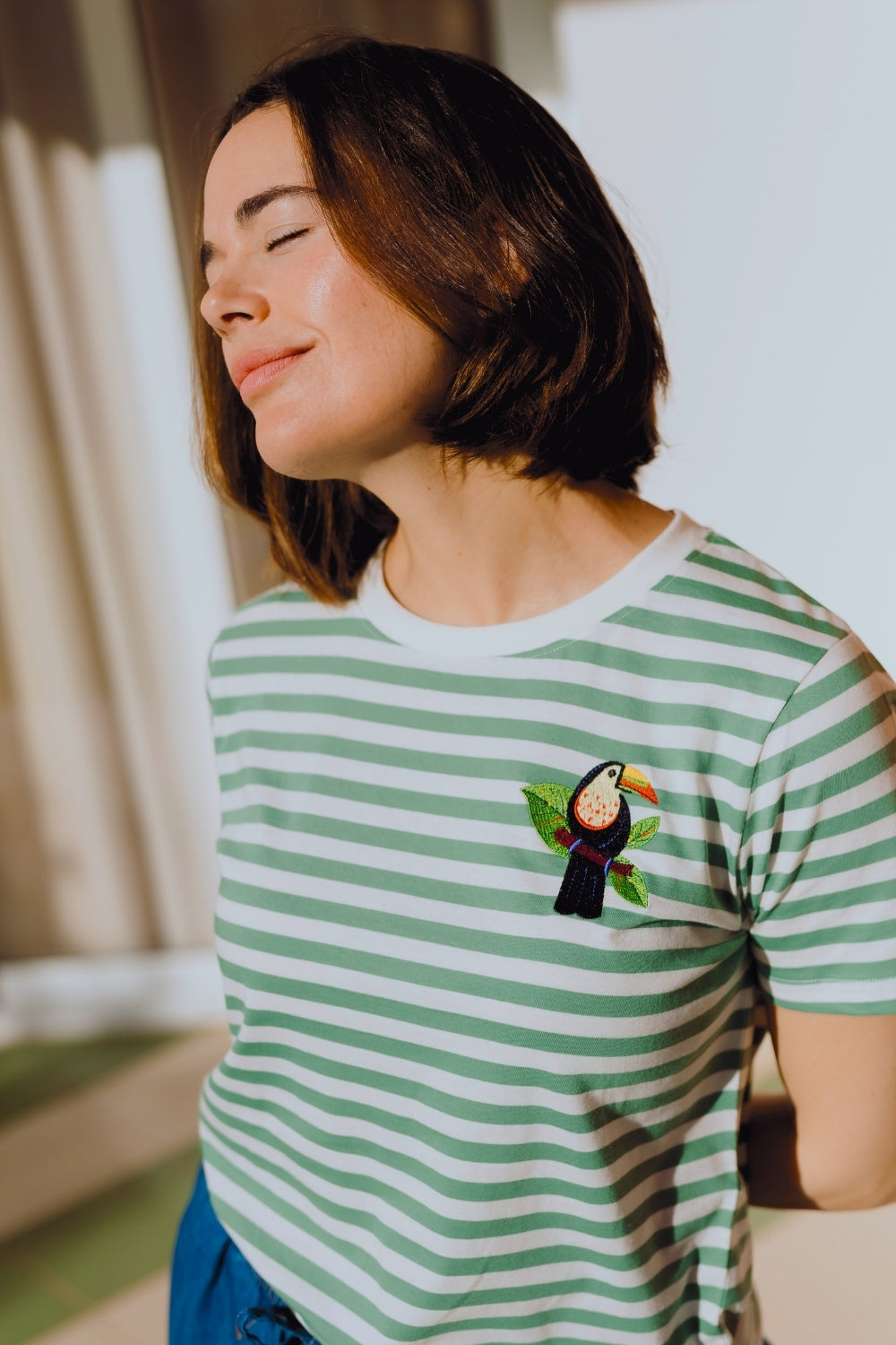 Person wearing a green and white striped t-shirt with a toucan design.