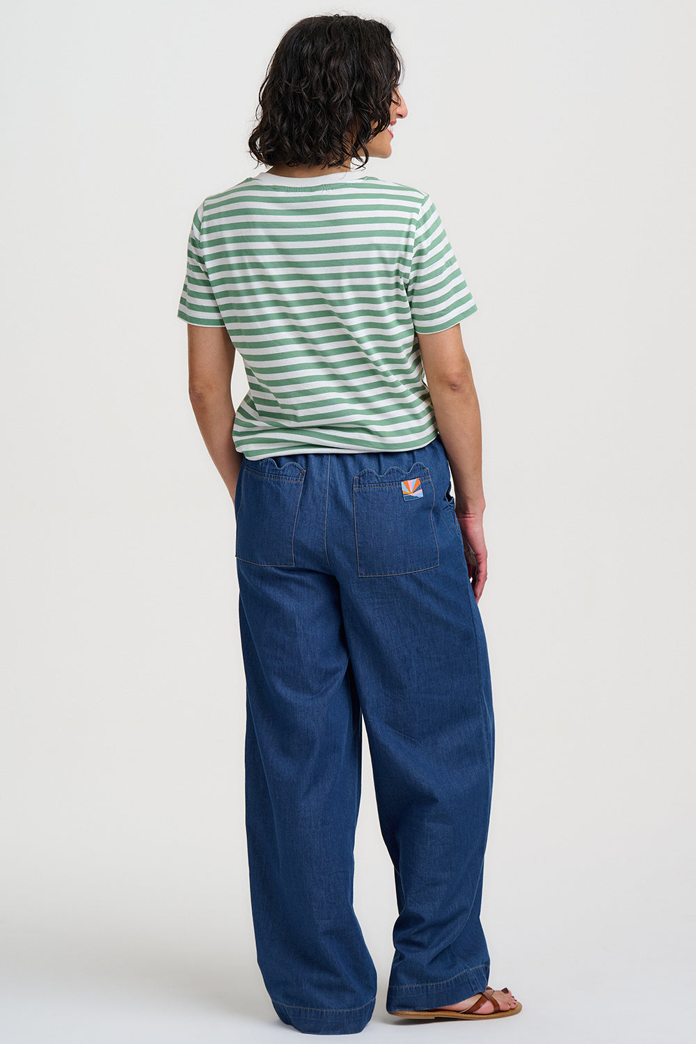 Person wearing a green and white striped shirt and blue pants on a white background