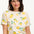 A woman smiling and wearing an off-white t-shirt with a lemon print design.