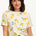 A woman smiling and wearing an off-white t-shirt with a lemon print design.