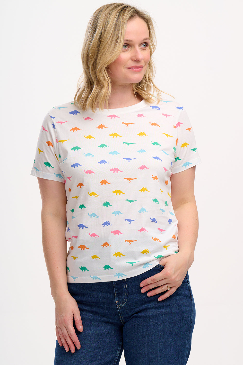 A woman wearing an off-white t-shirt with a colorful dinosaur print, paired with blue jeans.
