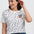 Woman wearing a white polka dot t-shirt with a colorful bird design on a plain background