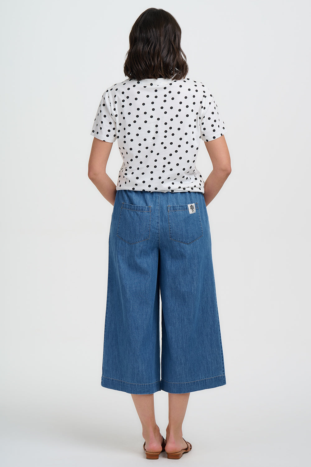 Person wearing a polka dot shirt and blue denim pants on a white background