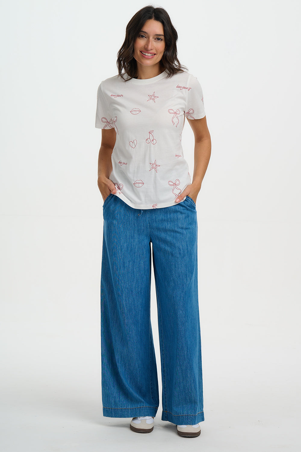 Woman wearing a white t-shirt with red graphics and blue pants on a white background