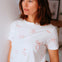 Woman wearing a white t-shirt with red patterns in a casual setting