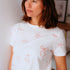 Woman wearing a white t-shirt with red patterns in a casual setting