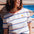 Person wearing a striped shirt with a flower design, standing against a colorful wooden wall.