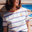 Person wearing a striped shirt with a flower design, standing against a colorful wooden wall.