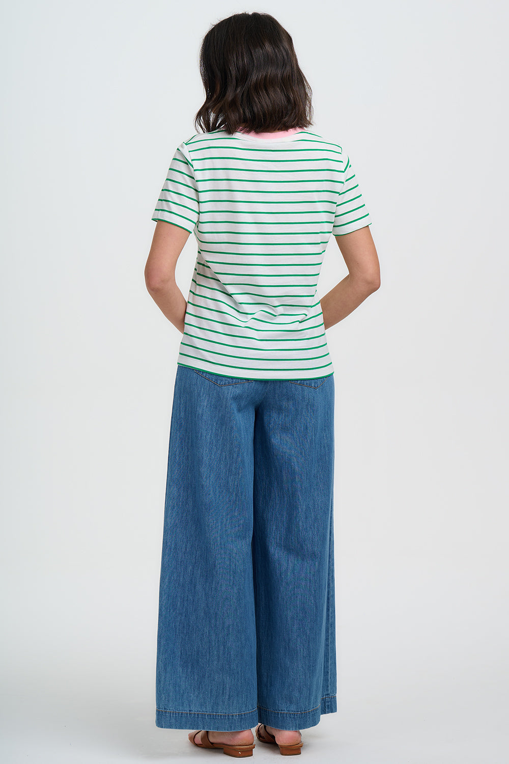 Woman wearing a striped shirt and wide-leg jeans on a white background