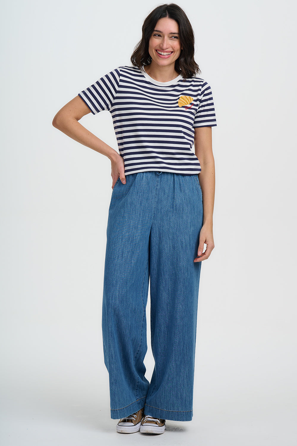 Woman wearing a striped shirt and blue pants on a white background