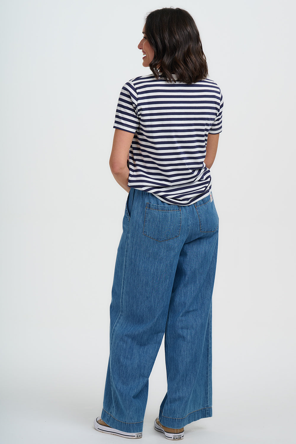 Person wearing a striped shirt and blue jeans on a white background
