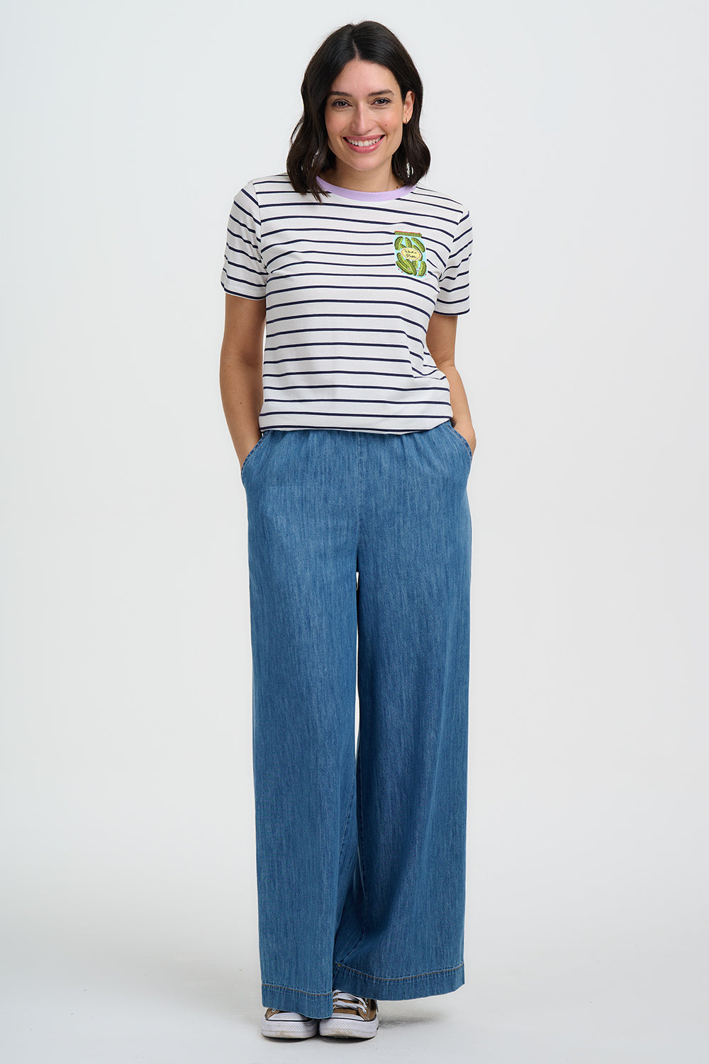 Woman wearing a striped shirt and wide-leg jeans on a white background