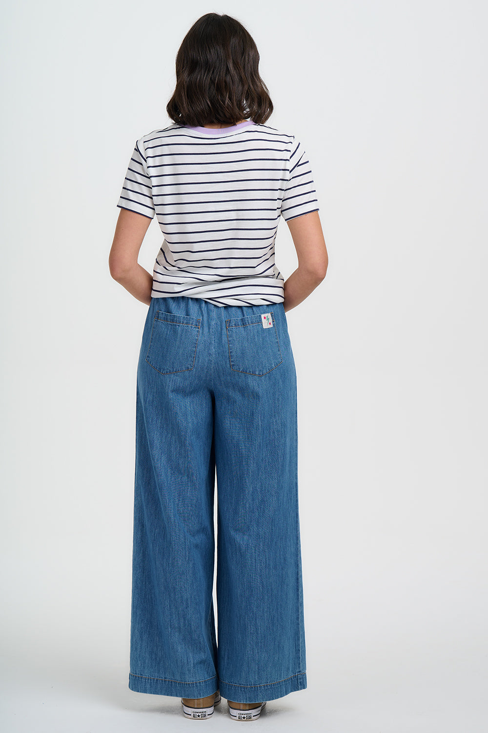 Person wearing a striped shirt and blue jeans on a white background