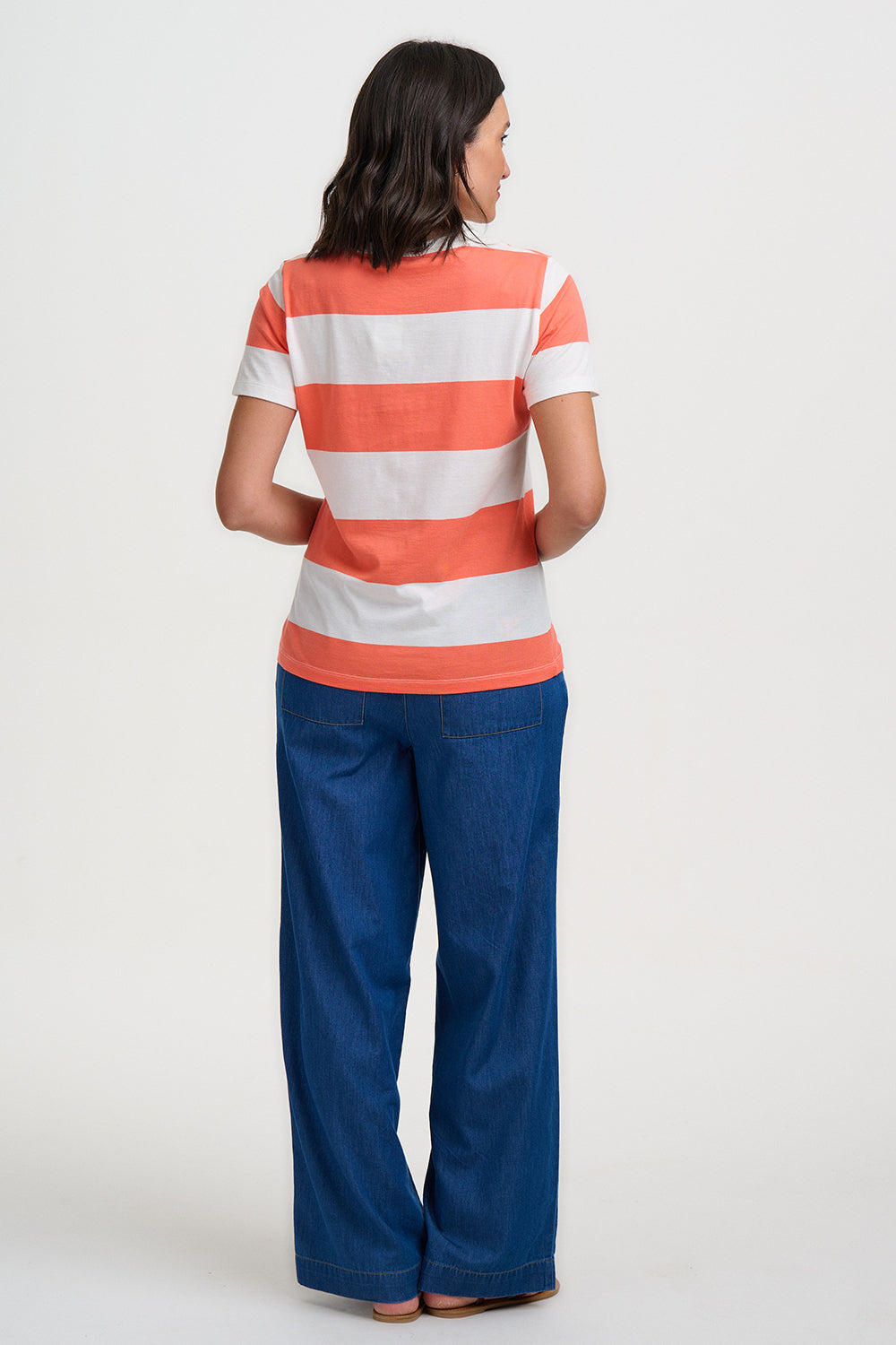 Person wearing a striped shirt and blue pants on a white background