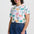 Woman wearing a colorful palm tree pattern shirt and blue shorts on a white background