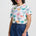 Woman wearing a colorful palm tree pattern shirt and blue shorts on a white background