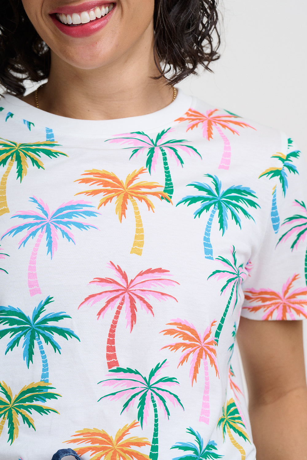 Person wearing a white t-shirt with colorful palm tree pattern