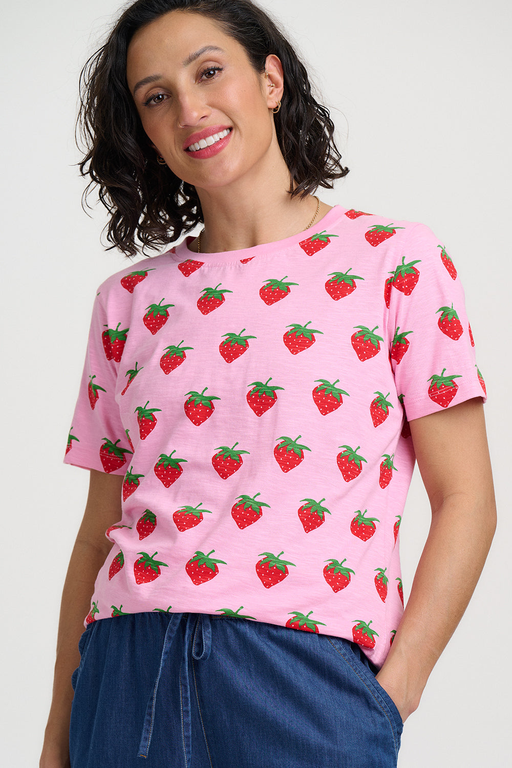 Woman wearing a pink t-shirt with strawberry pattern on a white background