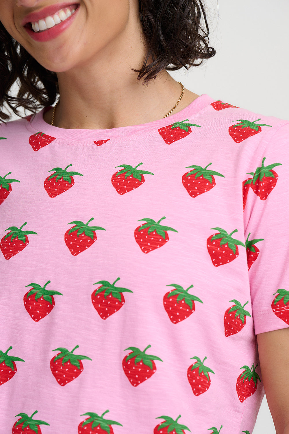 Person wearing a pink t-shirt with red strawberry patterns