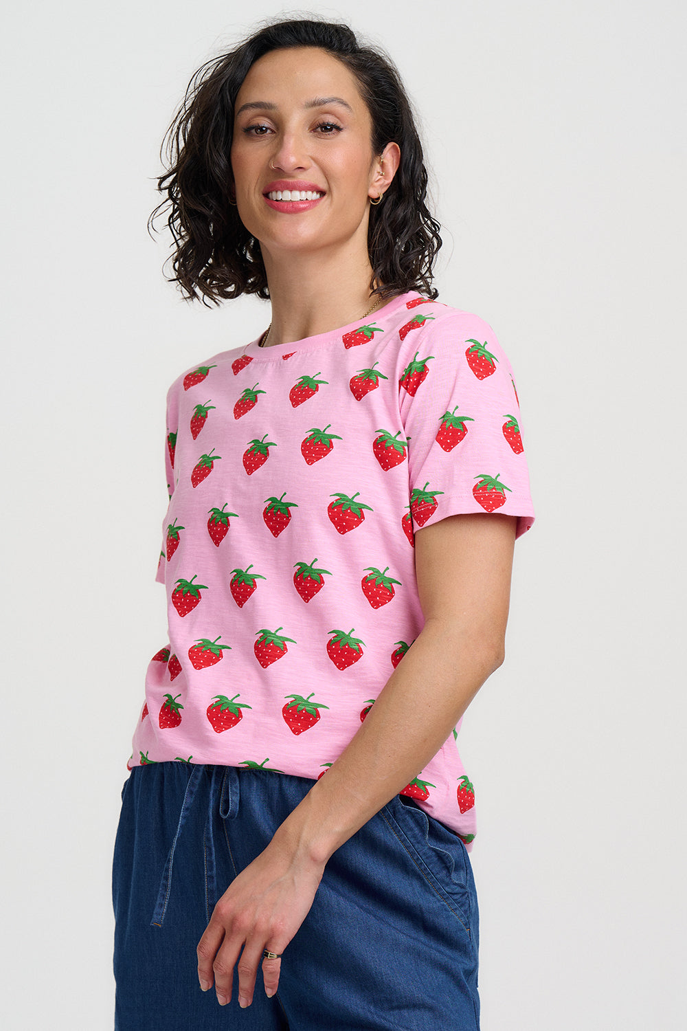 Woman wearing a pink t-shirt with strawberry pattern against a white background