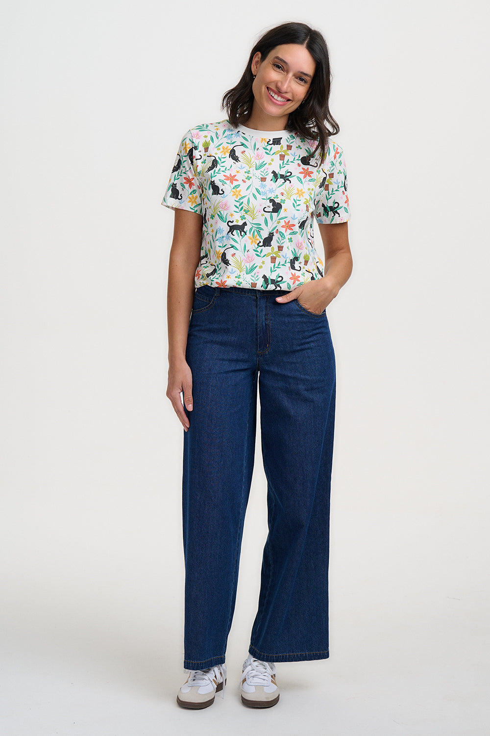 Woman wearing a colorful t-shirt with cat pattern and blue jeans on a white background