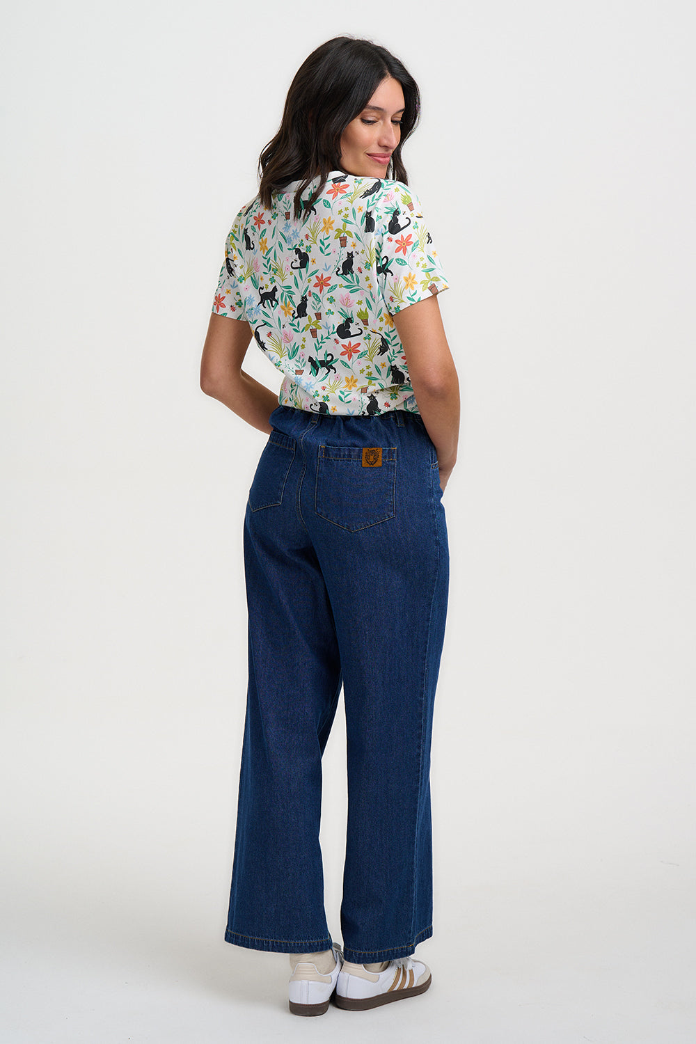 Woman wearing a floral blouse and blue jeans on a white background