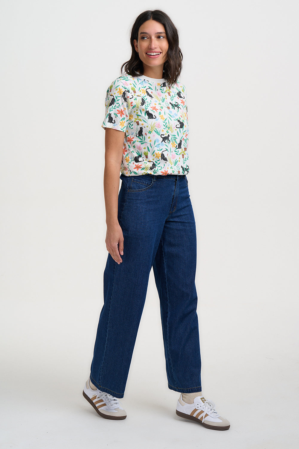 Woman wearing a colorful patterned shirt and blue jeans on a white background