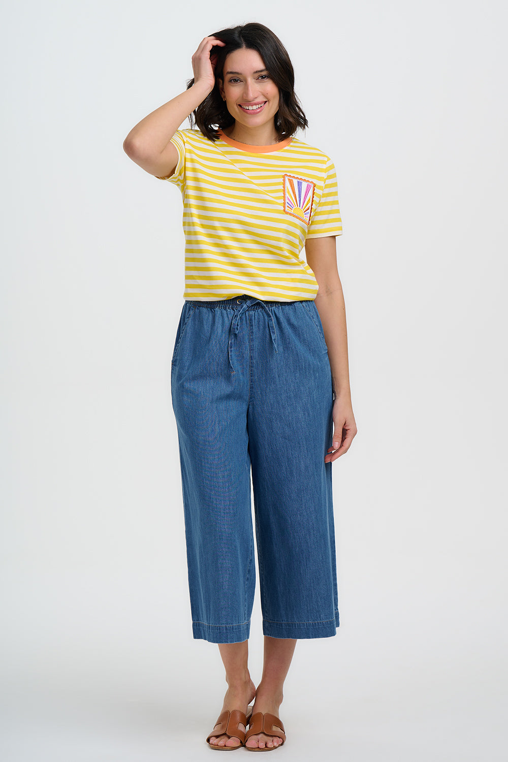 Woman wearing a yellow striped shirt and blue jeans on a white background