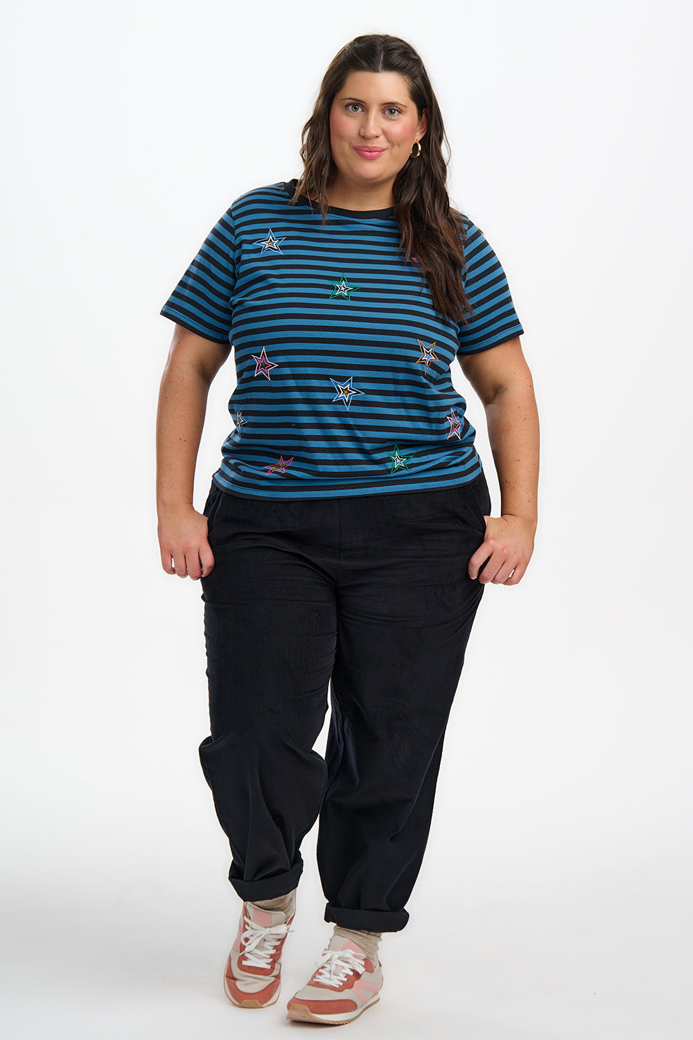 Woman wearing a blue striped shirt and black pants on a white background