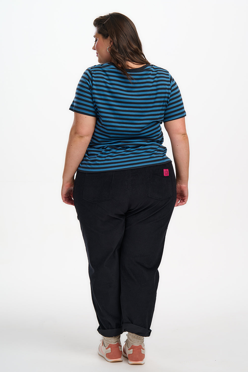 Person wearing a blue striped shirt and black pants on a white background