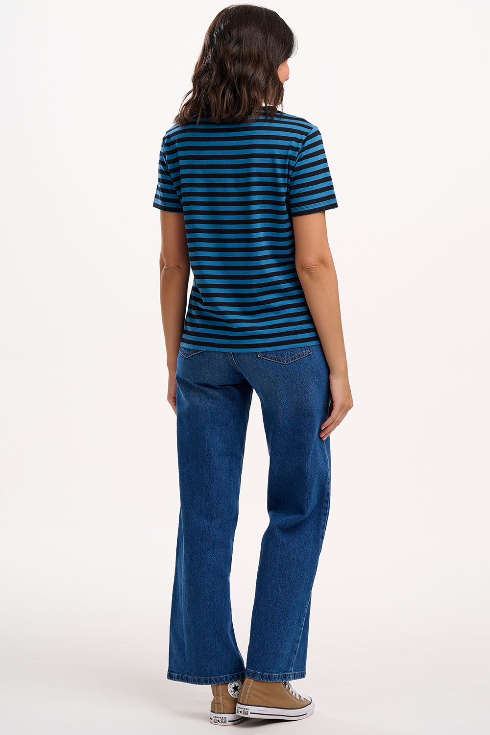 Person wearing a blue and black striped shirt and blue jeans on a white background