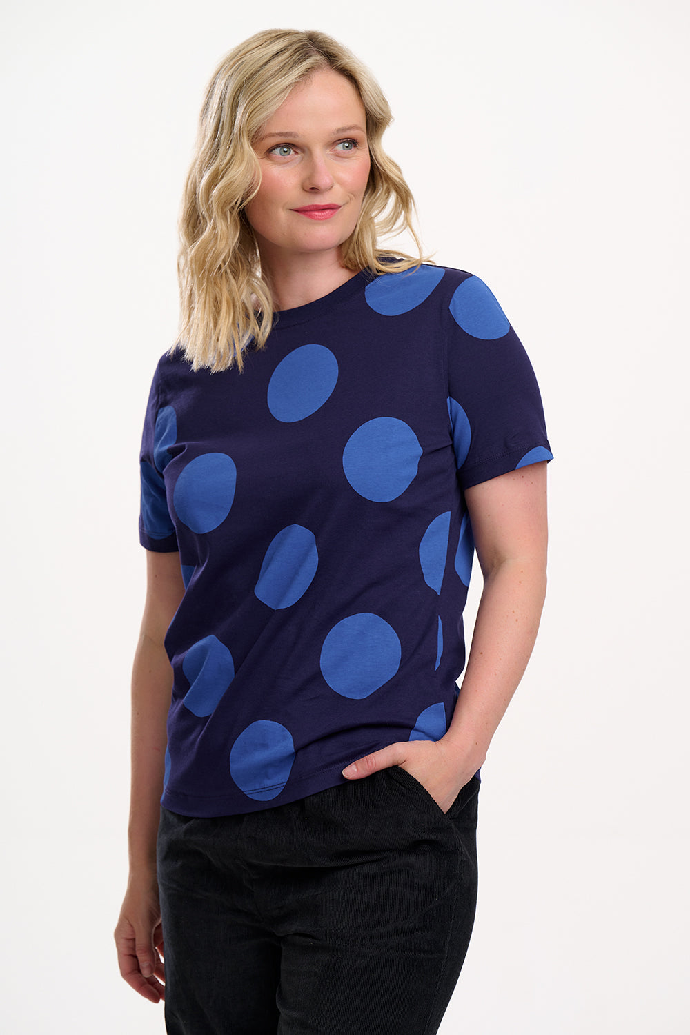 Woman wearing a navy blue top with large blue polka dots on a white background