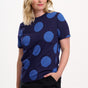 Woman wearing a navy blue top with large blue polka dots on a white background