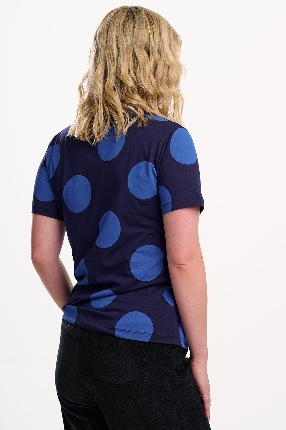 Person wearing a navy blue shirt with large blue polka dots on a white background