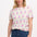 A female model wearing an off-white Maggie T-shirt with a cowgirl boots pattern in pink and blue, paired with blue jeans.