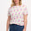 A female model wearing an off-white Maggie T-shirt with a cowgirl boots pattern in pink and blue, paired with blue jeans.