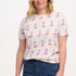 A female model wearing an off-white Maggie T-shirt with a cowgirl boots pattern in pink and blue, paired with blue jeans.