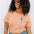 Person wearing an orange and white striped shirt with a blue parrot design, standing against a white background.