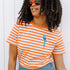Person wearing an orange and white striped shirt with a blue parrot design, standing against a white background.