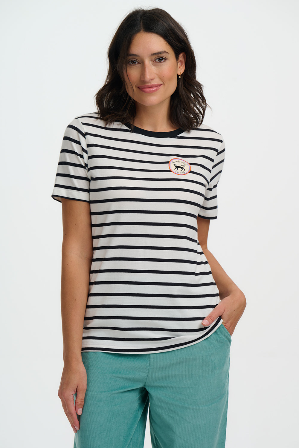 Woman wearing a black and white striped t-shirt with a small logo, standing against a plain background.